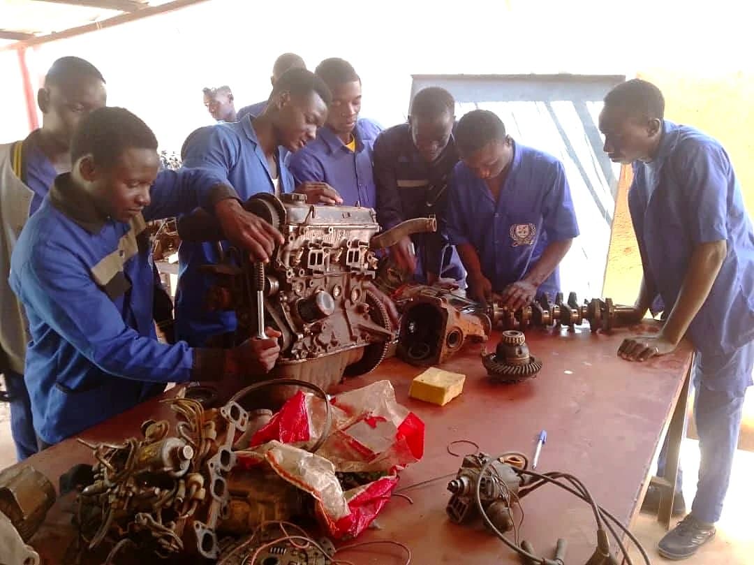 Groupe d'apprenants démontant un moteur en atelier de mécanique auto
