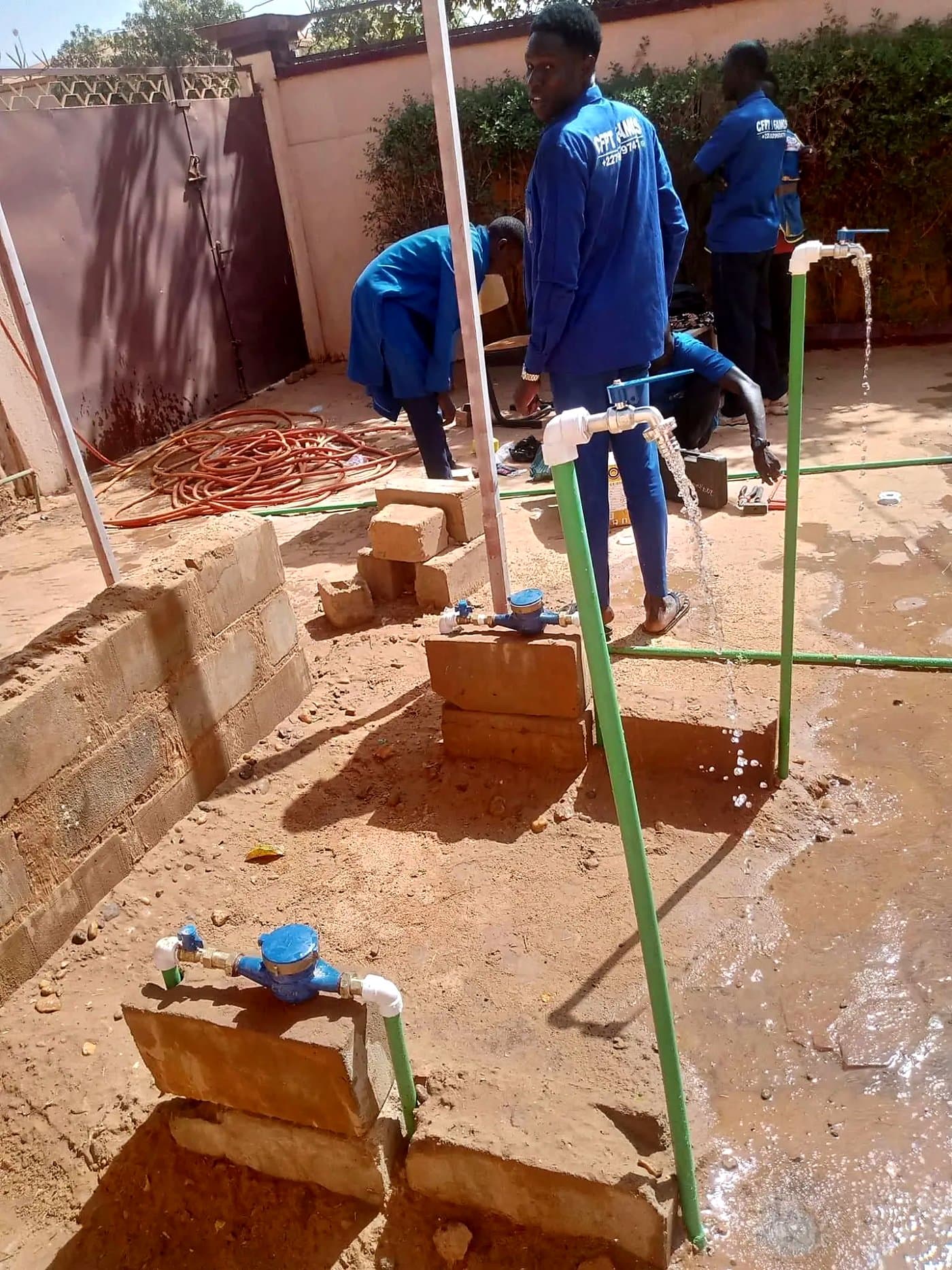 Apprenants en plomberie installant des canalisations et compteurs d'eau